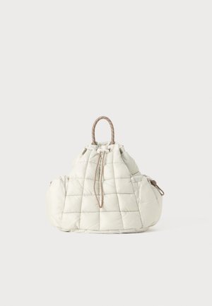 Quiltet off-white taske med snørelukning, polstrede sider og et enkelt løkkehåndtag i beige og hvidt trådarbejde.