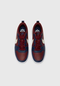 Ténis Nike com parte superior de couro azul-marinho e bordô, logótipo Swoosh branco, atacadores vermelhos, caixa de biqueira perfurada e sola branca.