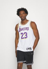 Bijela košarkaška dres s ljubičastim i žutim natpisom "LAKERS" i brojem 23. Nosio s crnim šortsem s bijelim prugama i Nike logom.