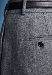 Gray felt trousers featuring a front pleat, side pocket, and a black button. A black leather belt complements the outfit.