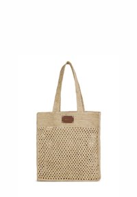Beige geweven draagtas met opengewerkt patroon en twee handgrepen, voorzien van een klein rechthoekig bruin label aan de bovenkant van de voorkant.