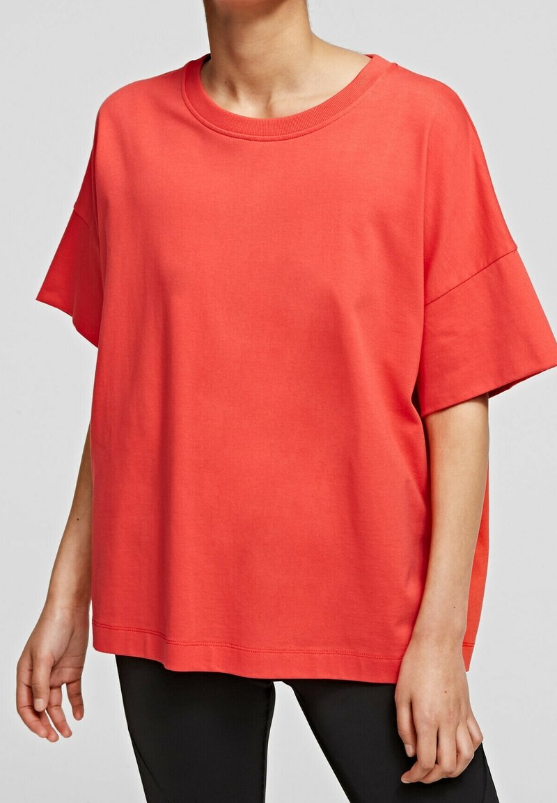 Rød bomulds T-shirt med løs pasform, rund halsudskæring og korte ærmer. Har minimal syning og en glat tekstur.