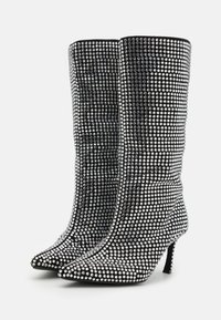 Botas negras hasta la rodilla cubiertas de cristales de plata, con punta afilada y tacón alto delgado, con una textura suave y un diseño ajustado.