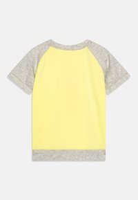 Camiseta de algodón amarilla con mangas raglán grises y un dobladillo a juego. Diseño simple con una textura suave, adecuada para uso casual.