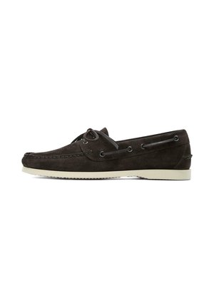 Chaussure bateau en daim marron foncé avec laçage à l'avant, couture moc toe, œillets latéraux et semelle en caoutchouc blanche sur fond blanc.