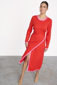 Rotes gestricktes Kleid mit pinken Akzenten und einem Rüschenausschnitt. Hat lange Ärmel und einen seitlichen Schlitz, was ein asymmetrisches Design schafft.
