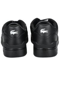 Paire de baskets en cuir noir vues de dos avec col rembourré et logos crocodile blancs sur les talons.