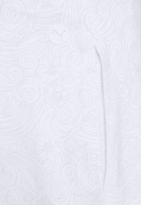 Tela blanca con un sutil patrón de remolinos y flores, con un logotipo circular. Textura suave con un detalle de costura a lo largo de las costuras.