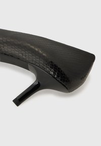 Scarpa nera con tacco alto, caratterizzata da una stampa di pelle di serpente testurizzata, punta arrotondata e sottile tacco a stiletto. Finitura liscia e punta affilata.