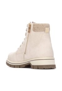 Bota de tobillo de ante beige con tela texturada en el cuello, cremallera lateral y suela de goma en contraste. Presenta acentos de herrajes metálicos.