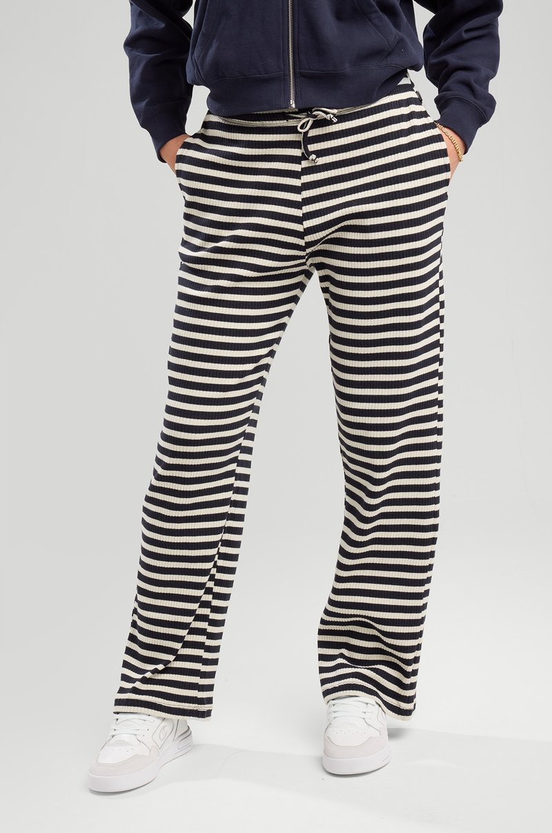 Striped pants in navy and cream, made from ribbed fabric. Features an elastic waistband with a drawstring and side pockets.