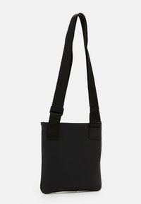 Black messenger bag with a textured surface, adjustable strap, and top closure. Features a simple rectangular design and minimal hardware.