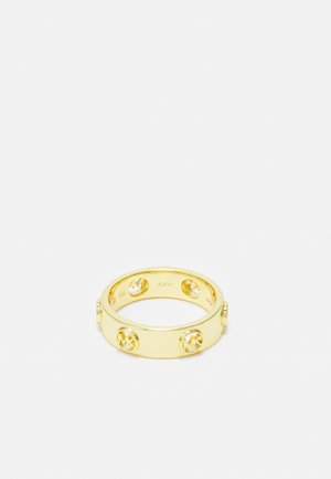 Bague en bande dorée avec des logos circulaires en relief espacés de manière régulière autour de la surface extérieure, sur un fond blanc uni.