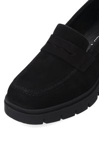 Mocassins en daim noir avec un design cousu, dotés d'un bout arrondi et d'une semelle en caoutchouc avec une légère plateforme. Style minimaliste sans accessoires.