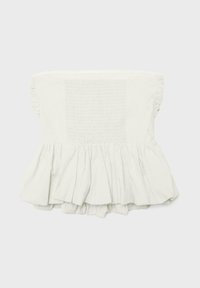 Haut bustier blanc avec ourlet à volants et panneau smocké à la poitrine, posé à plat sur fond clair.
