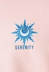 Rózsaszín textil, kék nap mintázattal, amelynek sugarai és egy félhold található, a "SERENITY" szöveggel, vastag betűtípussal.