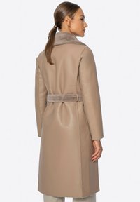 Beige Lederjacke mit einem weichen Fellkragen, taillierter Taille und gerader Silhouette. Hat nahtlose Nähte und ein mittellanges Design.