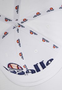 Biała czapka baseballowa z haftowanym logo i markową podszewką. Posiada płaski daszek, otwory wentylacyjne oraz miękką podszewkę.