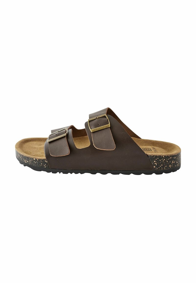 Braune Leder-Slidesandale mit zwei verstellbaren Riemen, goldenen Schnallen und einem Korkfußbett. Texturierte Sohle mit sprenkelnden Akzenten.