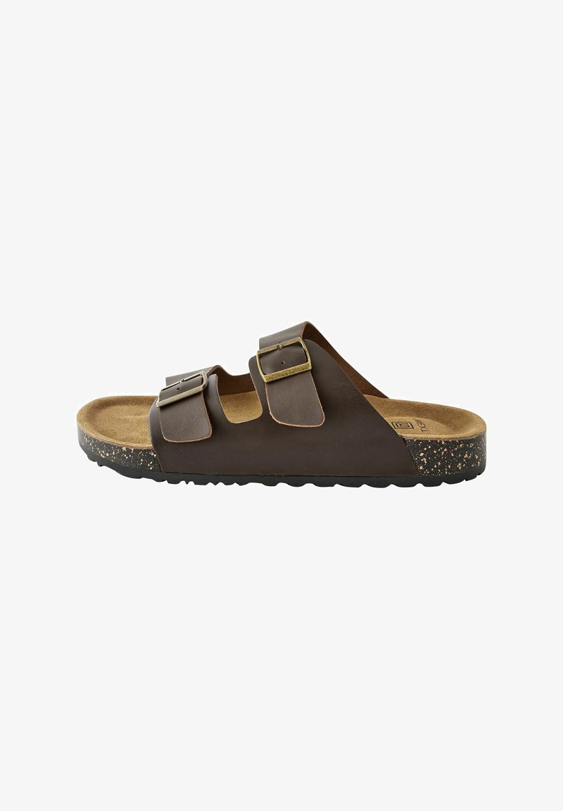 Braune Leder-Slidesandale mit zwei verstellbaren Riemen, goldenen Schnallen und einem Korkfußbett. Texturierte Sohle mit sprenkelnden Akzenten.