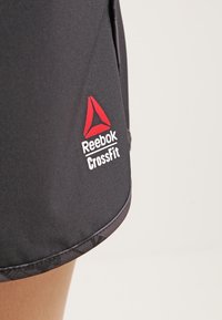 Svart träningsshorts i mjukt material, med en röd Reebok-logotyp och texten CrossFit på nederst till vänster.