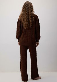 Brown cable-knit sweater and pants set, featuring long sleeves, ribbed hems, and a relaxed fit with a textured pattern throughout.