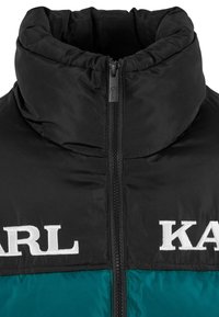 Czarna i morska kurtka puchowa z wysokim kołnierzem, zapięciem na zamek oraz białym logo "KARL" na piersi. Gładka, błyszcząca faktura.