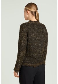 Sort og guld tekstureret sweater med frynset kant og manchetter, med lange ærmer og rund halsudskæring, vist bagfra.