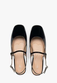Zwarte patent leren Mary Jane-schoenen met vierkante neuzen, verstelbare enkelband en een beige binnenzool met een hartpatroon.