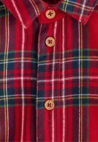 Chemise à carreaux rouge et marine avec un col boutonné, des boutons en bois et un tissu doux et texturé avec des lignes d'accent en blanc et jaune.