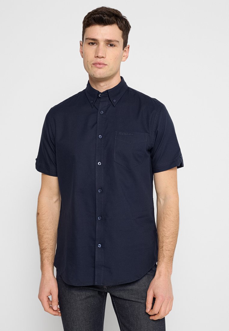 Chemise à manches courtes bleu marine, en mélange de coton, dotée d'une poche avant et de détails de couture subtils pour un look moderne et épuré.