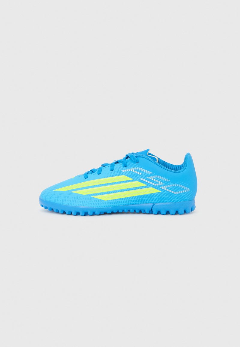 Chaussure de football bleu vif avec des rayures jaunes, semelle texturée et lacets, conçue pour le jeu sur gazon extérieur.