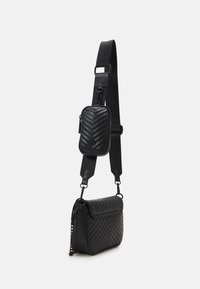 Borsa a tracolla nera in materiale trapuntato con motivo a zig zag; pochette piccola staccabile sul manico, con texture liscia e dettagli in metallo argentato.