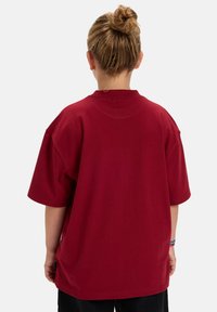 Rode oversized t-shirt met korte mouwen, een ronde hals en een comfortabele pasvorm. De stof lijkt zacht met een gladde textuur.