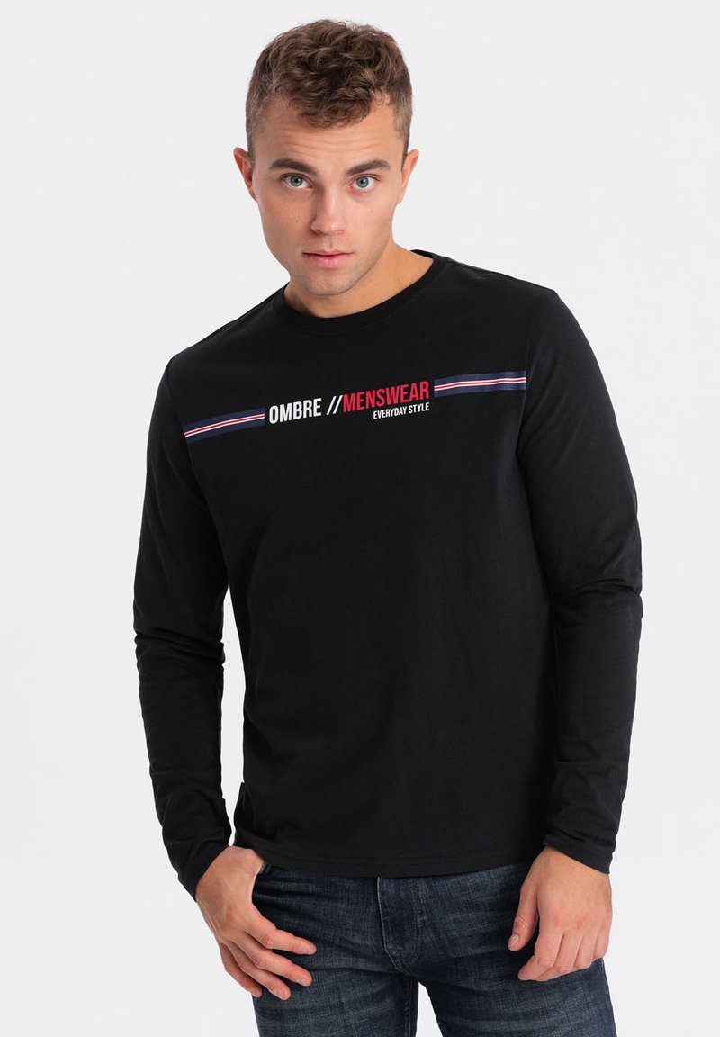 Schwarzes Langarm-T-Shirt aus Baumwolle mit dem bedruckten Text "OMBRE // MENSWEAR" in Rot und Weiß, versehen mit horizontalen Streifen in Blau und Rot.