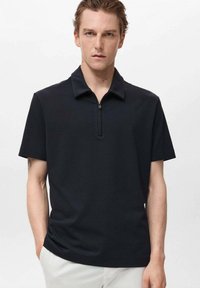 Černé polo tričko s krátkým rukávem a polo zapínáním. Má měkkou, hladkou texturu a design s ohnutým límcem.