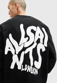 Sort sweatshirt med stor, legesyg hvid tekst, der læser "ALLSAINTS LONDON" på ryggen. Designet har en tekstureret overflade.