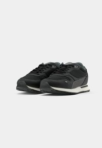 Zapatillas deportivas negras con un upper sintético suave, diseño de cordones, acentos grises y una media suela blanca en contraste. Suela de goma para tracción.