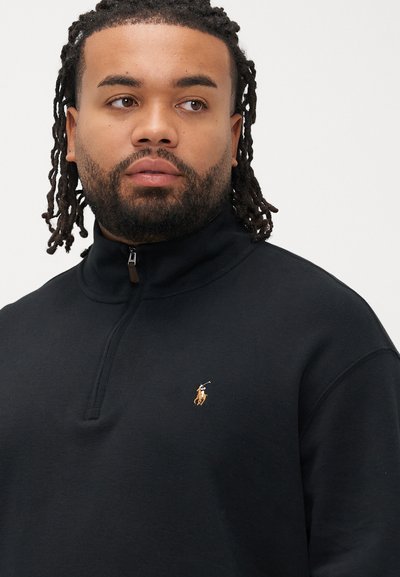 Μαύρο φούτερ με φερμουάρ και ψηλό γιακά, με μικρό κεντημένο λογότυπο στο στήθος. Κατασκευασμένο από λείο, υφασμένο ύφασμα.