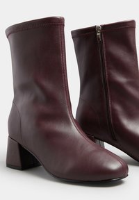 Bordowe skórzane botki za kostkę z blokowym obcasem, gładką teksturą, zaokrąglonym noskiem i bocznym zamkiem błyskawicznym, ułatwiającym zakładanie.