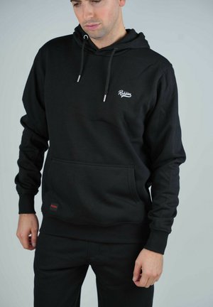 Le hoodie noir dispose d'une poche avant, d'une capuche avec cordon de serrage et d'un logo brodé sur la poitrine. Il est fabriqué en coton doux.