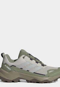 Chaussure de randonnée Adidas Terrex vert clair et beige avec semelle texturée, tige en mesh et marquage réfléchissant à trois bandes sur le côté.