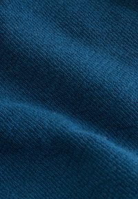 Prim-plan cu material texturat albastru care prezintă un model țesut și pliuri moi.