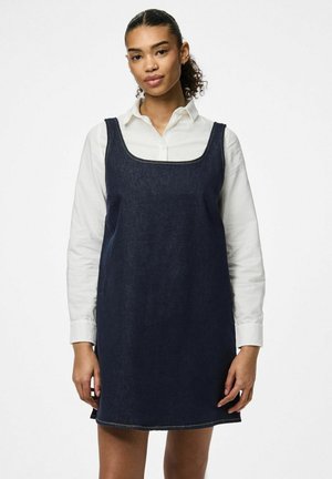 Robe en denim foncé avec un décolleté carré, coupe droite et sans manches, accompagnée d'une chemise blanche à col en dessous.