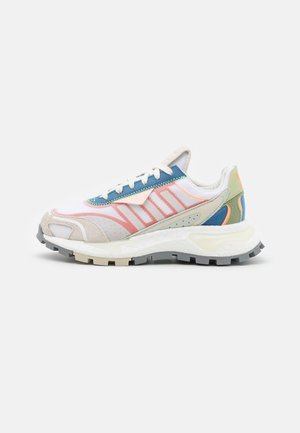 Lichtgewicht hardloopschoen met wit mesh, roze en blauwe accenten, beige suède overlays en een dikke witte zool met robuuste grijze buitenzool.