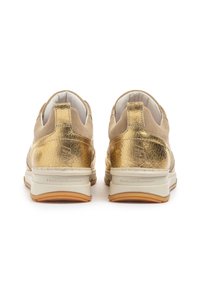 Zapatillas de ante doradas y beige con tacón metálico texturizado, forro blanco y suela de goma ligera. Muestra la marca en la parte trasera.