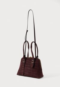 Tmavohnedá semišová taška s krokodílovou textúrou, dvojitými hornými držadlami, dlhým nastaviteľným ramenným popruhom a zlatým uzáverom na zips.