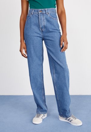 Light blue, high-waisted straight-leg jeans with front pockets and a button closure. Paired with grey sneakers featuring stripes.