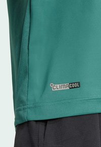 T-shirt de performance en teal avec des accents en mesh et l'étiquette CLIMACOOL, présentant une texture lisse et un design athlétique pour une meilleure respirabilité.