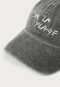 Cappellino da baseball in cotone grigio con ricamo bianco "SIR LA PLAGE." Presenta una visiera curva e un tessuto testurizzato. Design classico.
